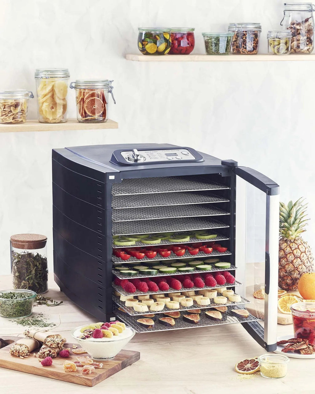 Voedseldroger gevuld met fruit en groenten, glazen potten.