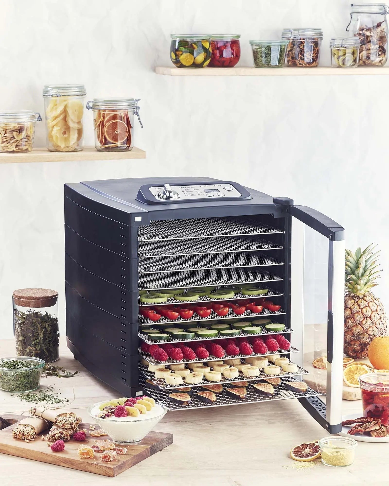 Voedseldroger gevuld met fruit en groenten, glazen potten.