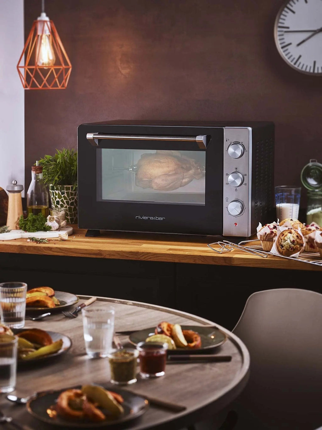 Braadoven van Riviera&Bar op een aanrecht met muffins en een gedekte eettafel.