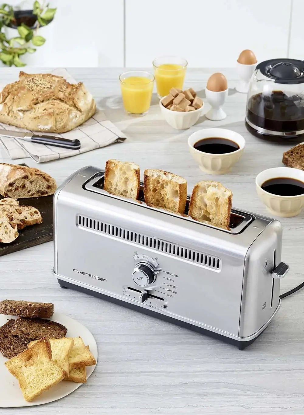 Roestvrijstalen broodrooster, brood, koffie, sinaasappelsap.