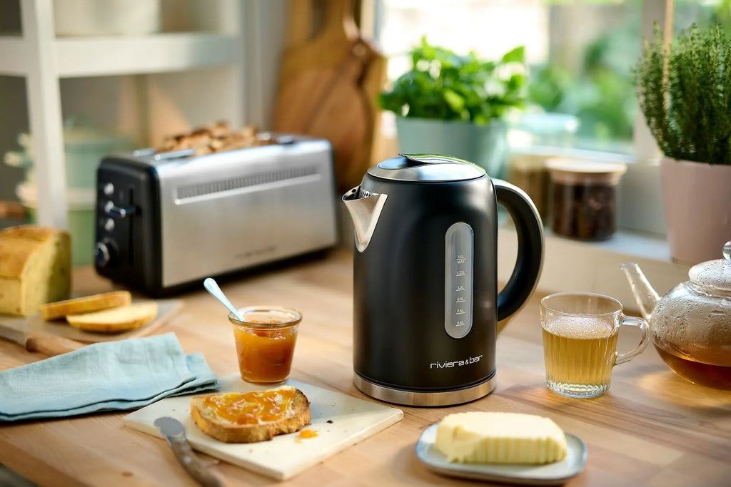 Zwarte waterkoker, brood, jam, theepot en boter.