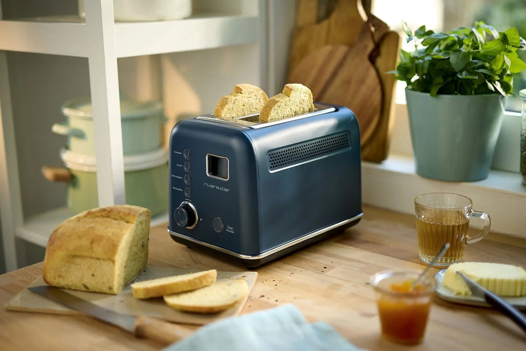 Blauwe broodrooster op een aanrecht met brood, jam en thee.