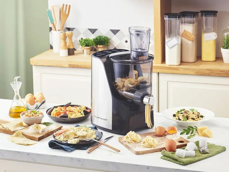 Zwart-witte elektrische pastamachine omringd door pastagerechten en verse ingrediënten.