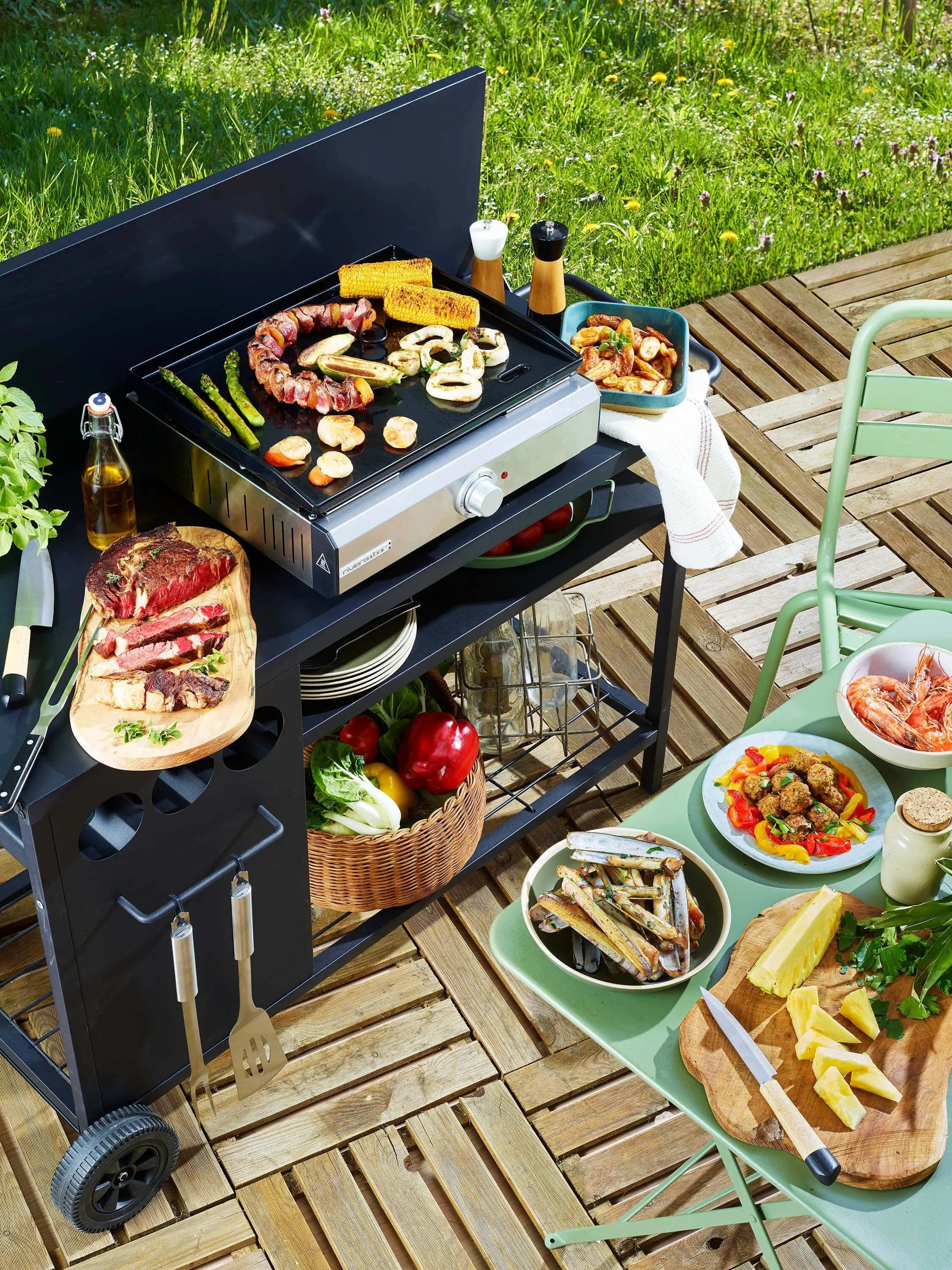 Barbecue met gegrild vlees, groenten en fruit op een houten terras.