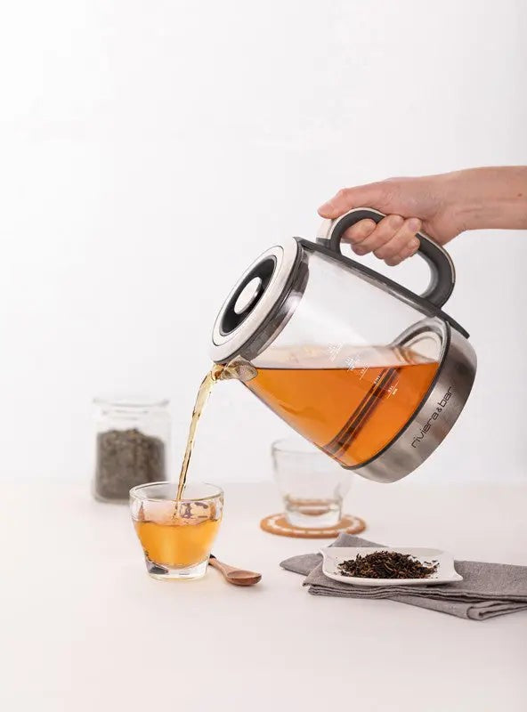 Glazen theepot schenkt thee in een glas.