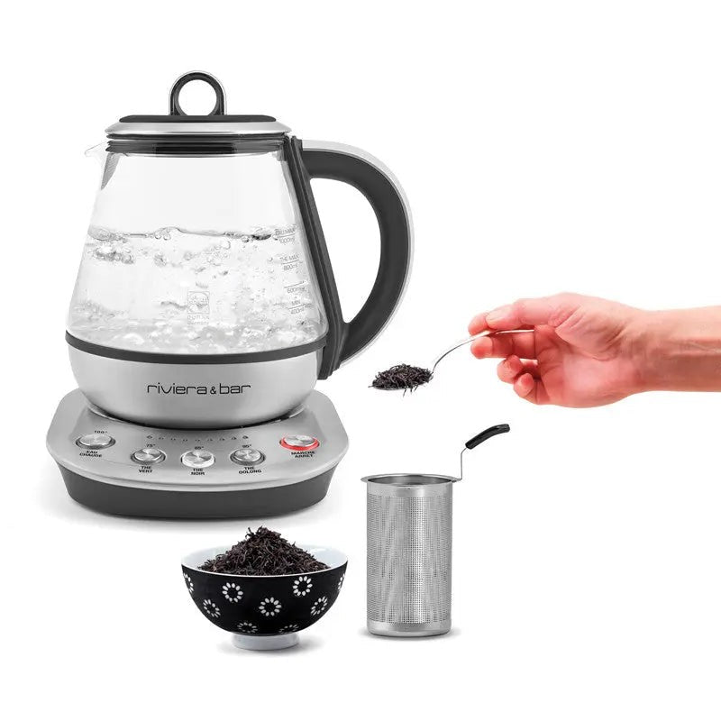 Glazen theepot, roestvrijstalen basis, metalen infuser, zwarte theekom.